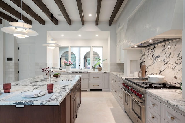 kitchen with double oven range, light stone counters, white cabinets, decorative light fixtures, and custom exhaust hood