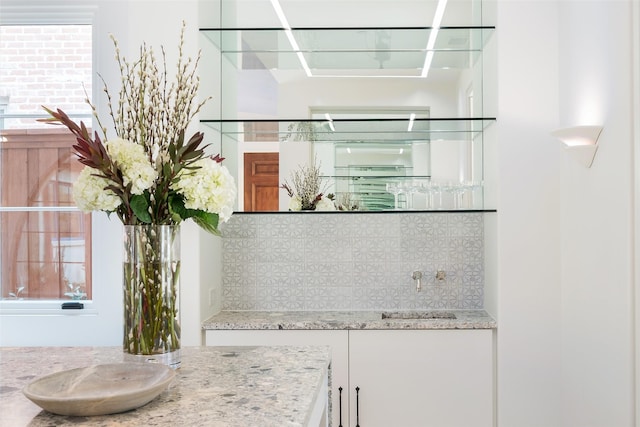 interior space featuring tasteful backsplash, light stone countertops, sink, and a wealth of natural light