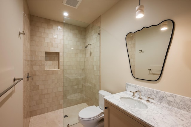 bathroom with vanity, tiled shower, and toilet