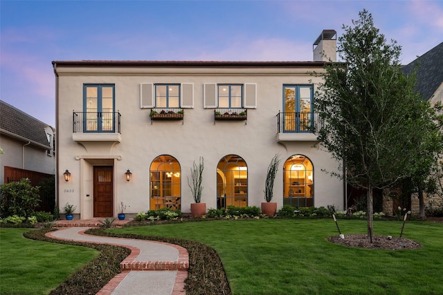 view of front of house with a balcony and a lawn