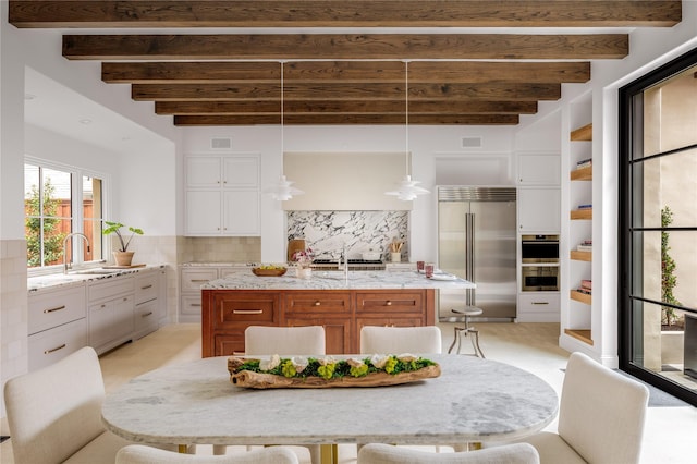 kitchen with white cabinetry, beamed ceiling, tasteful backsplash, and stainless steel built in fridge