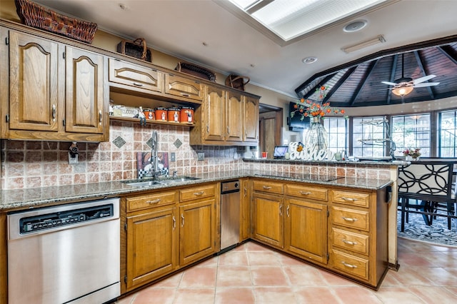 kitchen with lofted ceiling, ceiling fan, stone countertops, stainless steel dishwasher, and kitchen peninsula