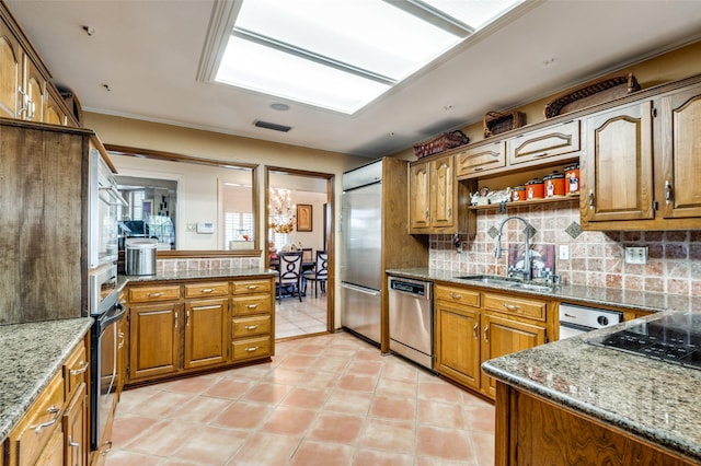 kitchen with stainless steel appliances, stone countertops, sink, and decorative backsplash