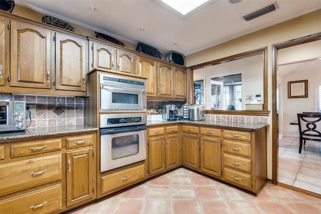 kitchen featuring light stone counters, crown molding, decorative backsplash, and light tile patterned floors