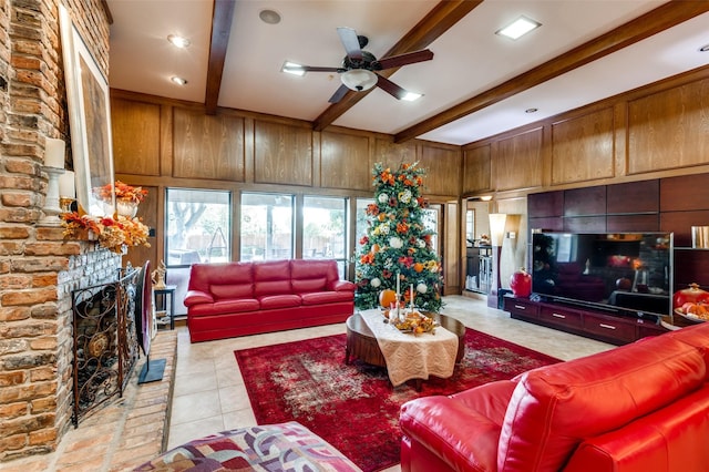 tiled living room featuring beamed ceiling, ceiling fan, a brick fireplace, and wooden walls