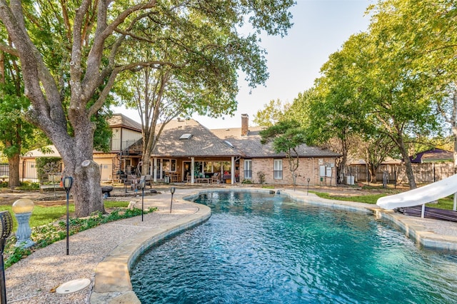 view of swimming pool with a water slide and a patio area