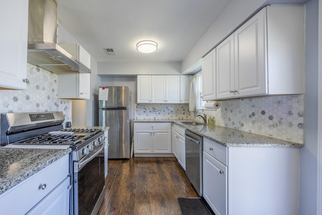 kitchen with white cabinetry, extractor fan, light stone counters, and appliances with stainless steel finishes