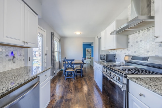 kitchen with stainless steel appliances, dark hardwood / wood-style floors, light stone counters, white cabinets, and wall chimney exhaust hood