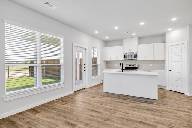 3842-3844 Clovis St, Midlothian, TX 76065 - kitchen with appliances with stainless steel finishes, decorative backsplash, a center island with sink, light countertops, and white cabinets