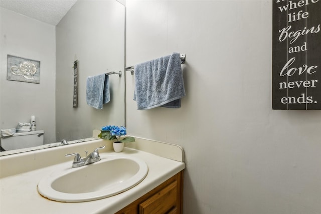 bathroom with vanity, toilet, and a textured ceiling