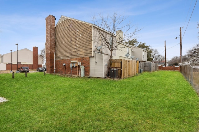 view of side of property with central AC and a yard