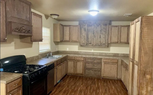 kitchen featuring sink, dark wood-type flooring, black gas range, tile countertops, and stainless steel dishwasher