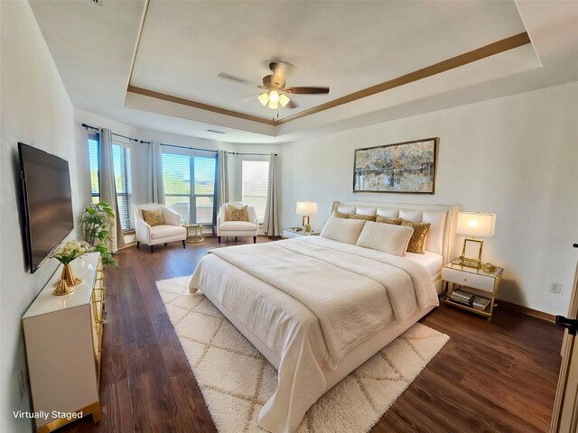 unfurnished room featuring ceiling fan, dark wood-type flooring, a raised ceiling, and a healthy amount of sunlight