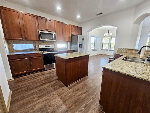 kitchen featuring pendant lighting, sink, dark hardwood / wood-style flooring, decorative backsplash, and stainless steel appliances