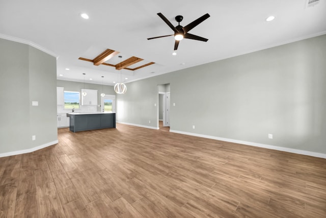 unfurnished living room featuring sink, crown molding, ceiling fan, and light wood-type flooring