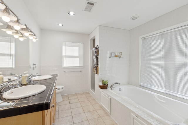 full bathroom with plus walk in shower, tile walls, vanity, toilet, and tile patterned floors