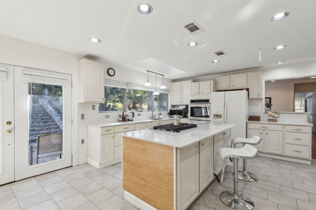 kitchen featuring a kitchen bar, hanging light fixtures, a kitchen island, a wealth of natural light, and stainless steel appliances