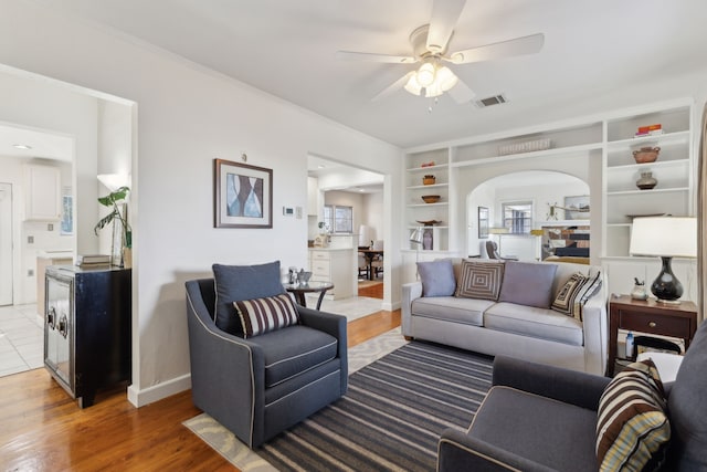 living room featuring hardwood / wood-style flooring, built in features, and ceiling fan