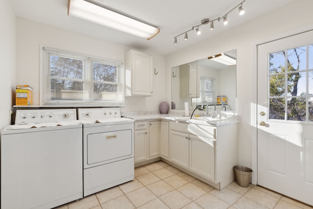 clothes washing area featuring light tile patterned floors, cabinets, washing machine and dryer, and sink