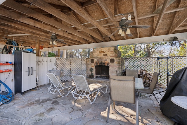 view of patio with ceiling fan and an outdoor stone fireplace