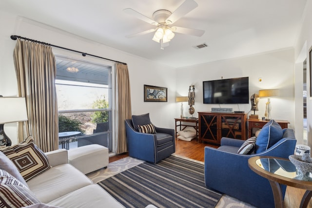 living room featuring hardwood / wood-style flooring, ornamental molding, and ceiling fan