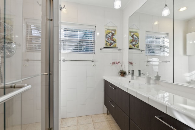 bathroom featuring tile patterned floors, vanity, a shower with shower door, and tile walls