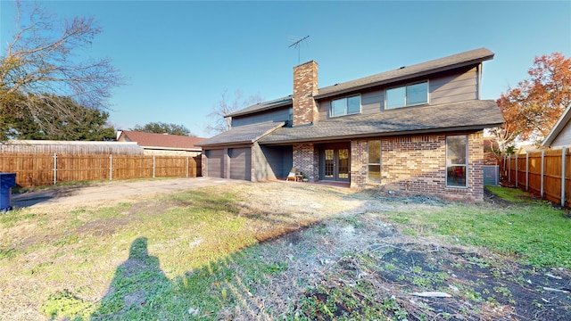 back of house featuring a garage and a lawn