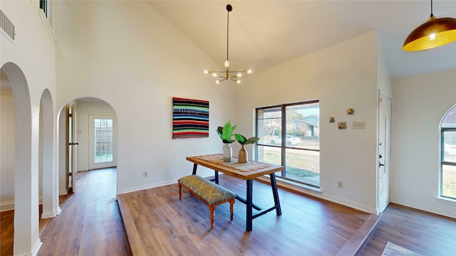 dining room with a notable chandelier, hardwood / wood-style flooring, plenty of natural light, and high vaulted ceiling