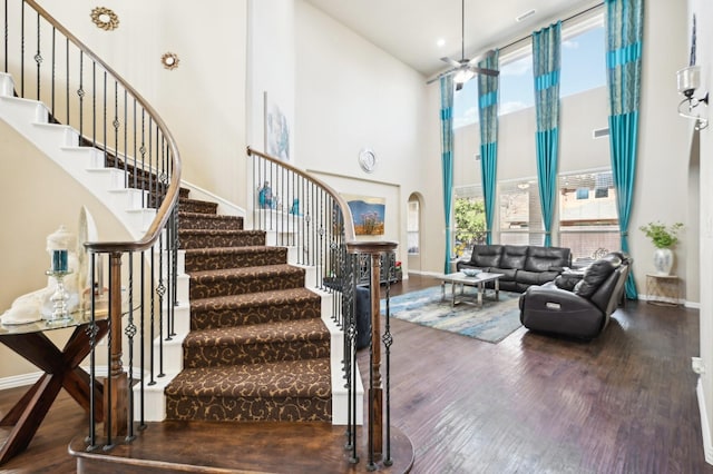 staircase featuring ceiling fan, hardwood / wood-style floors, and a high ceiling