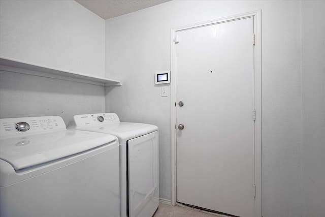 laundry area with washing machine and clothes dryer and a textured ceiling