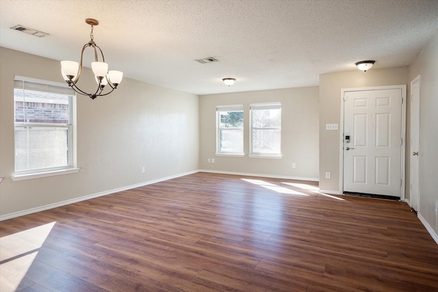 interior space with a notable chandelier, dark hardwood / wood-style flooring, a textured ceiling, and a wealth of natural light