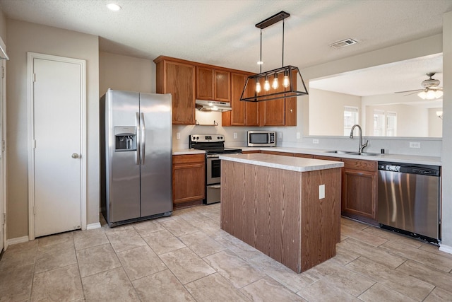 kitchen featuring appliances with stainless steel finishes, sink, pendant lighting, and a textured ceiling