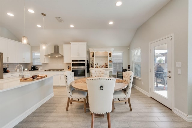 dining room featuring vaulted ceiling, a wealth of natural light, and visible vents