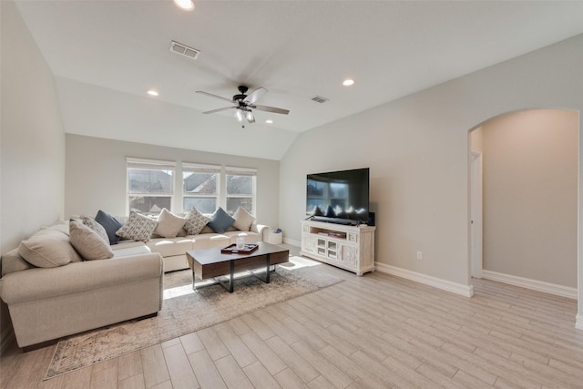 living room with arched walkways, visible vents, light wood-style flooring, vaulted ceiling, and ceiling fan