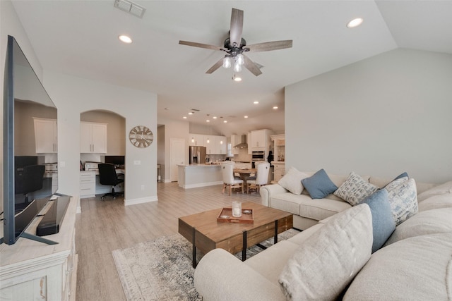 living room featuring lofted ceiling, light wood finished floors, visible vents, and recessed lighting