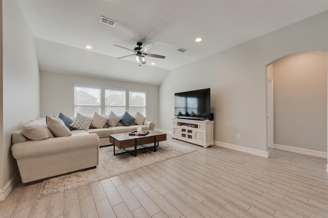 living area featuring lofted ceiling, light wood-style flooring, visible vents, and arched walkways