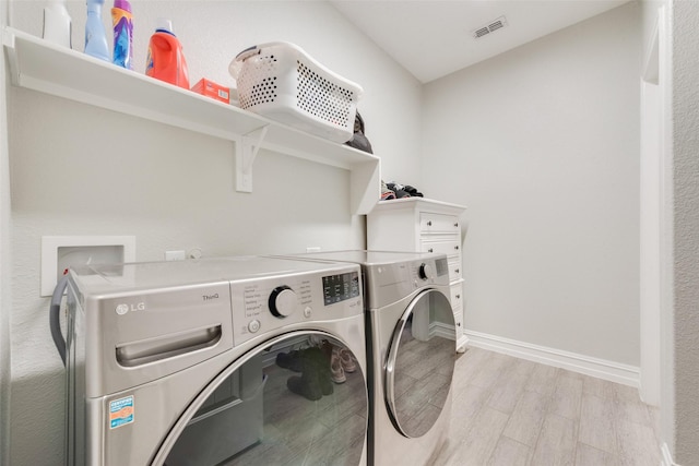 laundry area with laundry area, baseboards, visible vents, washer and dryer, and light wood-type flooring