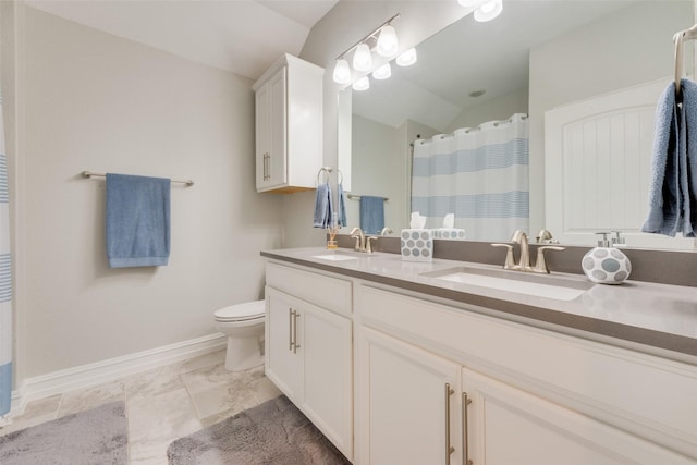 full bathroom with baseboards, a sink, toilet, and double vanity