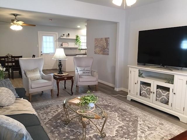 living room featuring ceiling fan and dark hardwood / wood-style floors