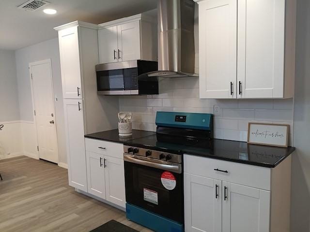 kitchen featuring white cabinetry, stainless steel appliances, tasteful backsplash, wall chimney exhaust hood, and light wood-type flooring