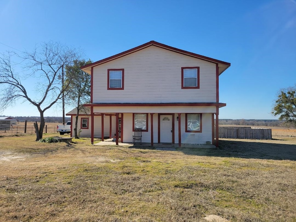 view of front of house with a front yard and a rural view