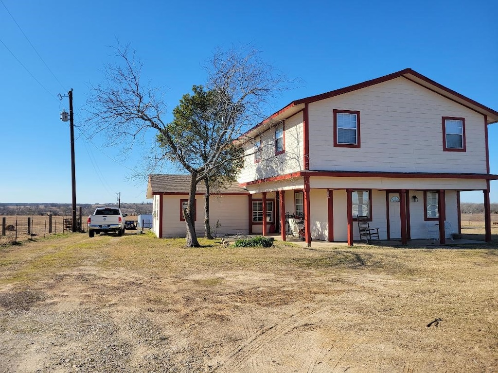 rear view of property featuring a porch and a lawn