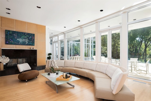 living room featuring a wall of windows, a tiled fireplace, and light wood-type flooring