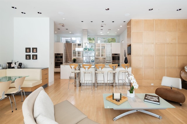 living room with sink, light hardwood / wood-style floors, and expansive windows