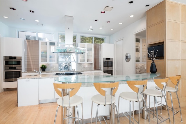 kitchen featuring appliances with stainless steel finishes, a breakfast bar area, light stone counters, and a spacious island