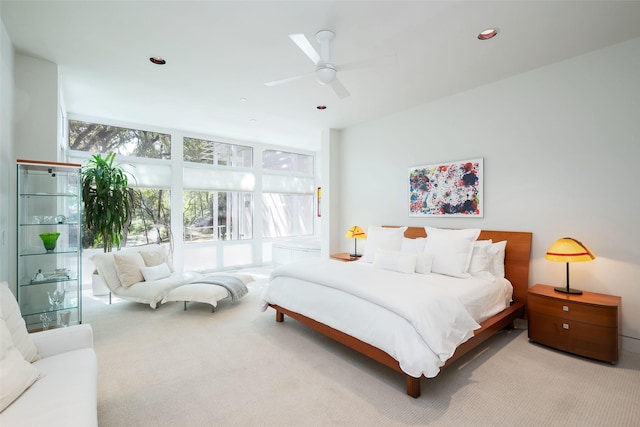 bedroom featuring light carpet, floor to ceiling windows, and ceiling fan