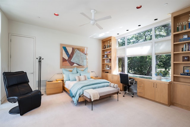 carpeted bedroom with ceiling fan and built in desk