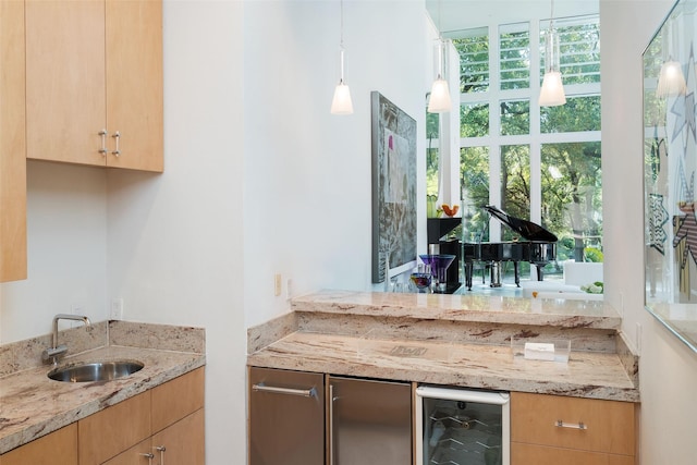 interior space featuring pendant lighting, sink, light stone counters, and beverage cooler