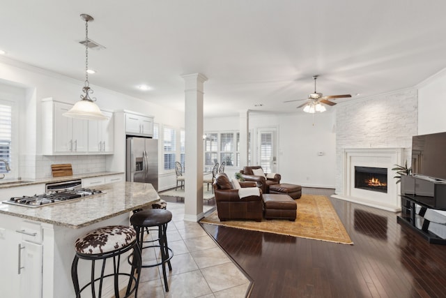 kitchen featuring a breakfast bar area, appliances with stainless steel finishes, light stone countertops, white cabinets, and decorative light fixtures