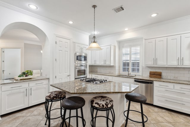 kitchen with a kitchen island, sink, white cabinets, stainless steel appliances, and light stone countertops